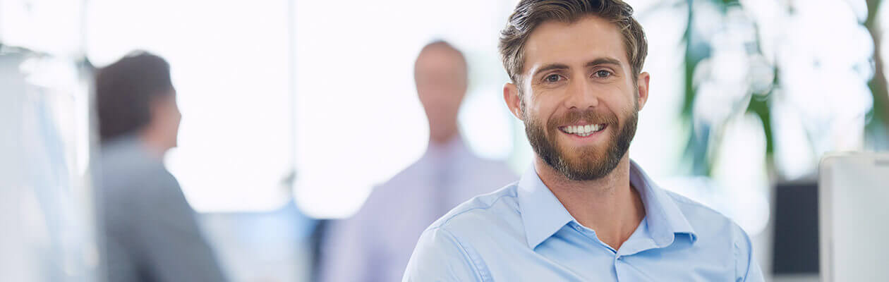 young male paralegal smiling in an office wearing a blue shirt