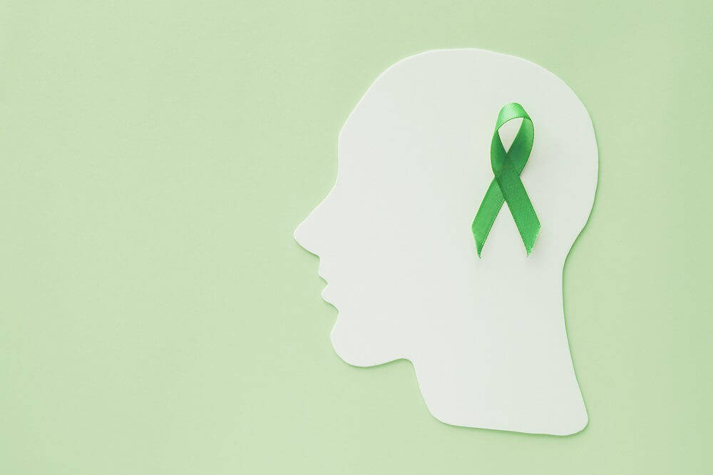 human head on a green background with the mental health awareness ribbon